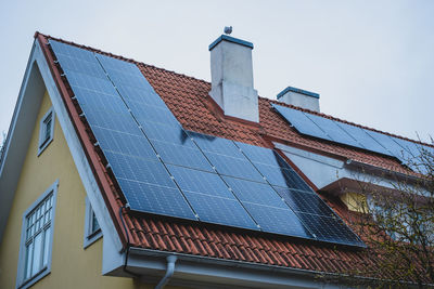 Close-up of solar panels installed on historic building gable roof with chimney.