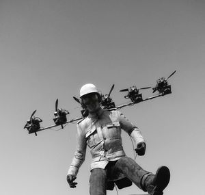 Low angle view of men standing against clear sky