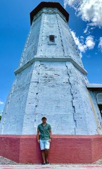 Low angle view of man standing by the cape bejeador lighthouse in burgos, ilocos norte. 