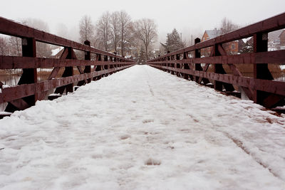 Snow covered footbridge against sky