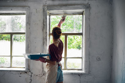 Rear view of woman standing by window