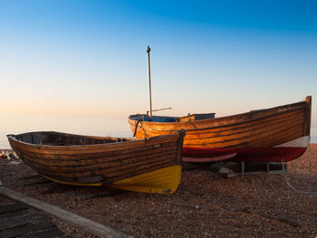 Two boats moored on shore against clear blue sky