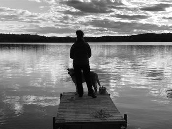 Rear view of woman on pier over lake against sky