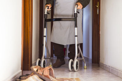 Low section of man with walker standing on tiled floor