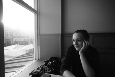 Portrait of man sitting on window at home