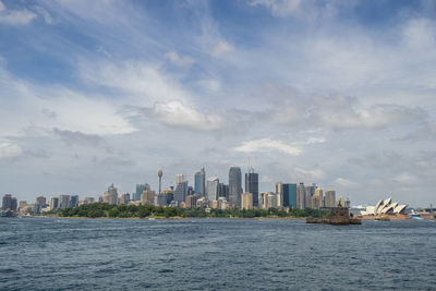 Sea by buildings against sky in city