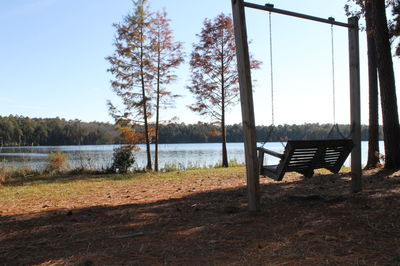 Empty bench by lake against sky