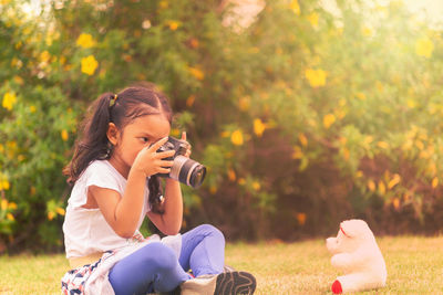 Girl holding toy while sitting on plants