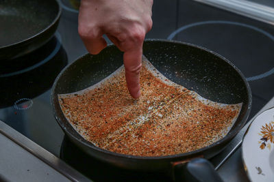 Person pointing on spices in frying pan