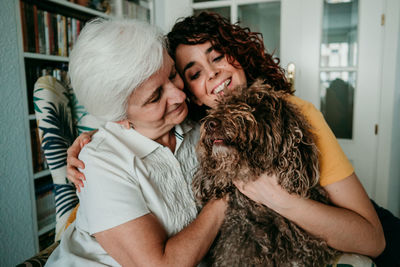 Smiling woman with dog and mother at home