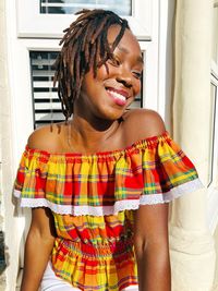 Portrait of young woman standing against wall