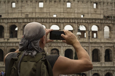 Rear view of man photographing amphitheater with mobile phone 