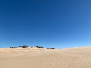 Scenic view of desert against clear blue sky