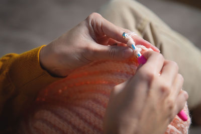 Female hands close-up, crocheting clothes on the sofa at home, handmade