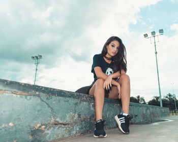 Portrait of young woman sitting against sky