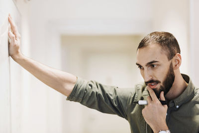 Thoughtful businessman holding felt tip pen in office