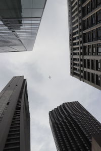 Low angle view of modern buildings against sky with airplane in the center. in chicago 