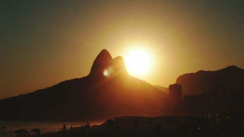 Silhouette mountains by sea against clear sky during sunset