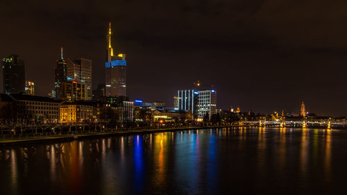 Illuminated city buildings by river at night