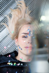 Portrait of woman with confetti on face lying down 