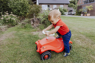 Full length of cute girl playing with toy car on field