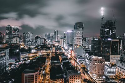 High angle view of cityscape against cloudy sky at night