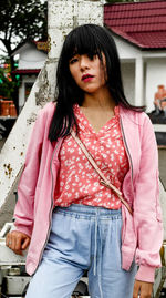 Portrait of young woman with bangs standing in city