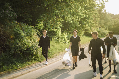 Man walking with happy boys and garbage bags on road