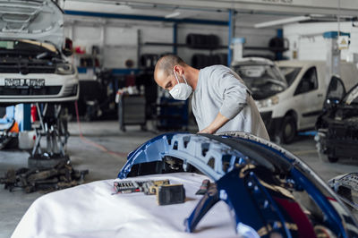 Auto mechanic analyzing bumper in repair shop