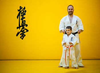 Portrait of smiling girl standing against yellow wall