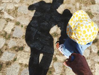 Cropped image of father holding daughter hand while walking on street