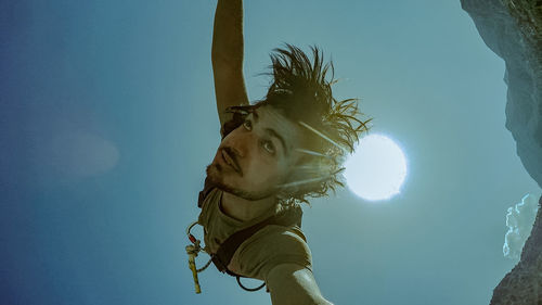 Low angle view of man hanging against clear sky