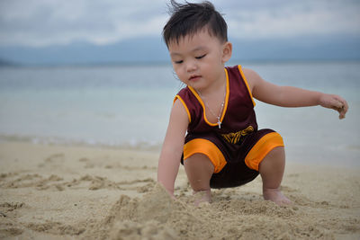 Close-up of boy playing on beach against sky