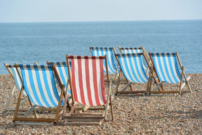 Deck chairs on beach against sky