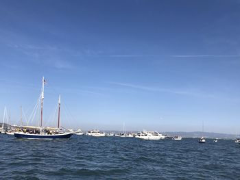 Sailboats sailing in sea against blue sky