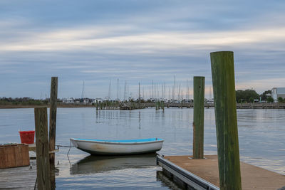 Wooden posts moored in sea against sky