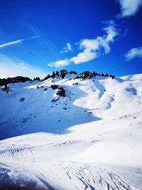 Scenic view of snow covered mountains against blue sky