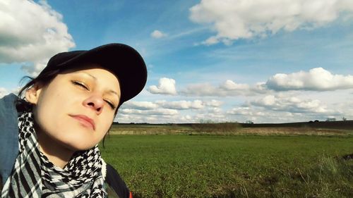 Close-up of woman wearing cap against field