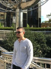 Young man looking away while standing by railing