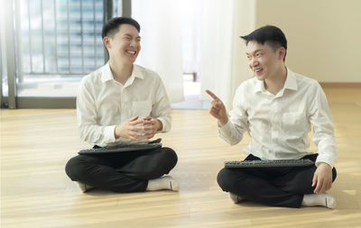 Happy young man sitting on floor