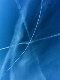 Low angle view of vapor trails in blue sky