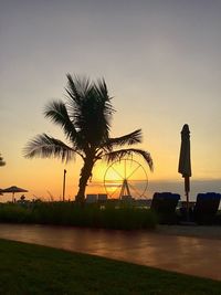 Silhouette palm trees on beach against sky at sunset