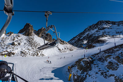 Ski lift over snowcapped mountains against sky