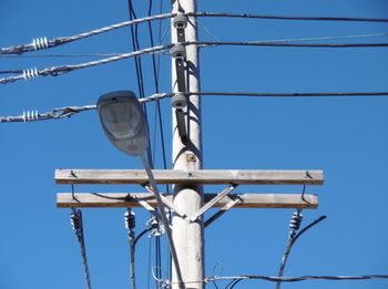 Low angle view of power lines against clear blue sky