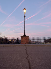 Low angle view of illuminated street light in front of road against sky at dusk