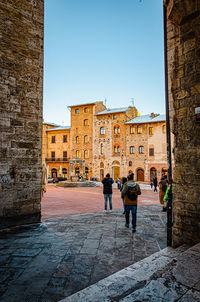 Rear view of people walking against buildings in city