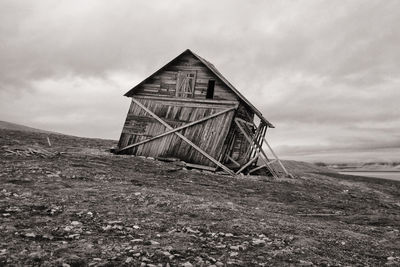 Abandoned house on field against sky