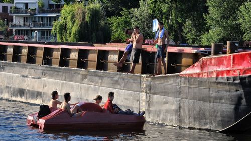 People on boat in canal against trees