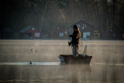 Man standing on boat against river