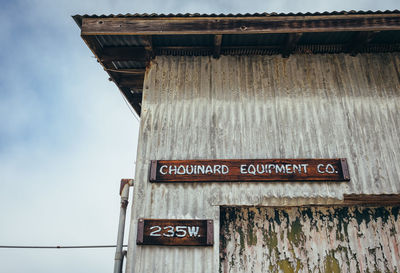 Low angle view of text on old building against sky